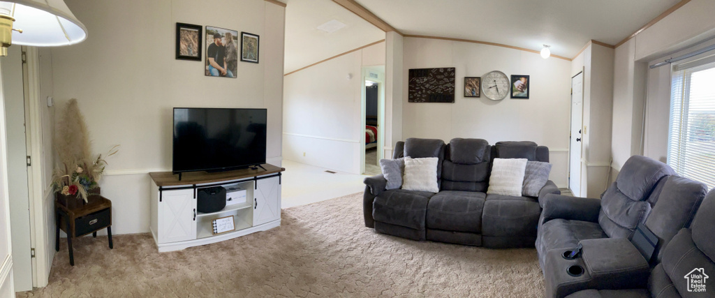 Living room featuring crown molding, lofted ceiling, and light colored carpet