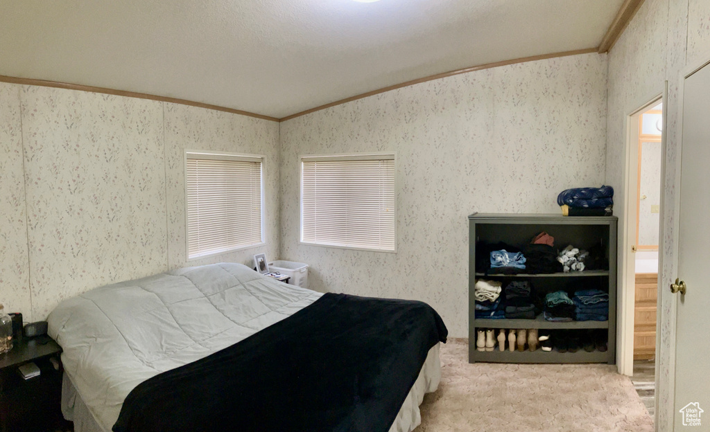 Bedroom featuring crown molding, vaulted ceiling, and light carpet