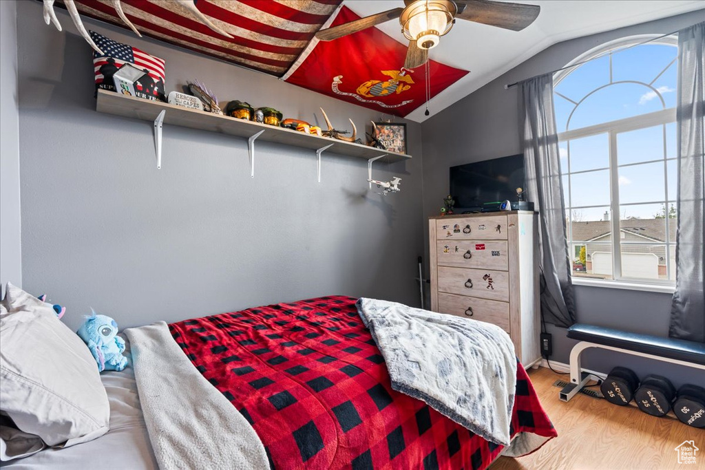 Bedroom featuring ceiling fan, hardwood / wood-style flooring, and lofted ceiling