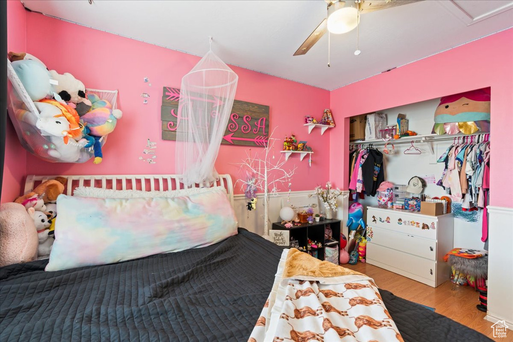 Bedroom with a closet, ceiling fan, wood-type flooring, and a crib