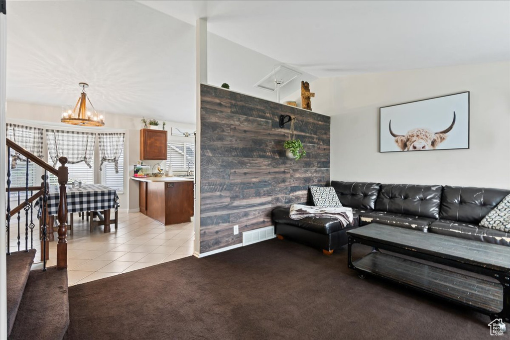 Living room featuring an inviting chandelier, lofted ceiling, and light colored carpet