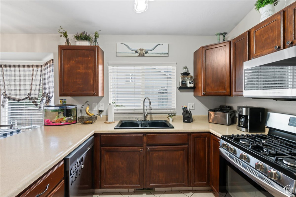 Kitchen with stainless steel appliances, sink, and light tile patterned floors