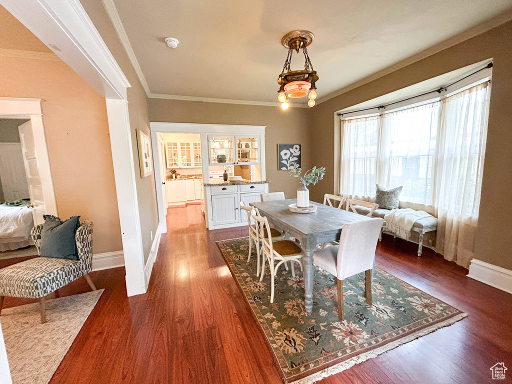 Dining room with ornamental molding, a chandelier, and dark hardwood / wood-style floors