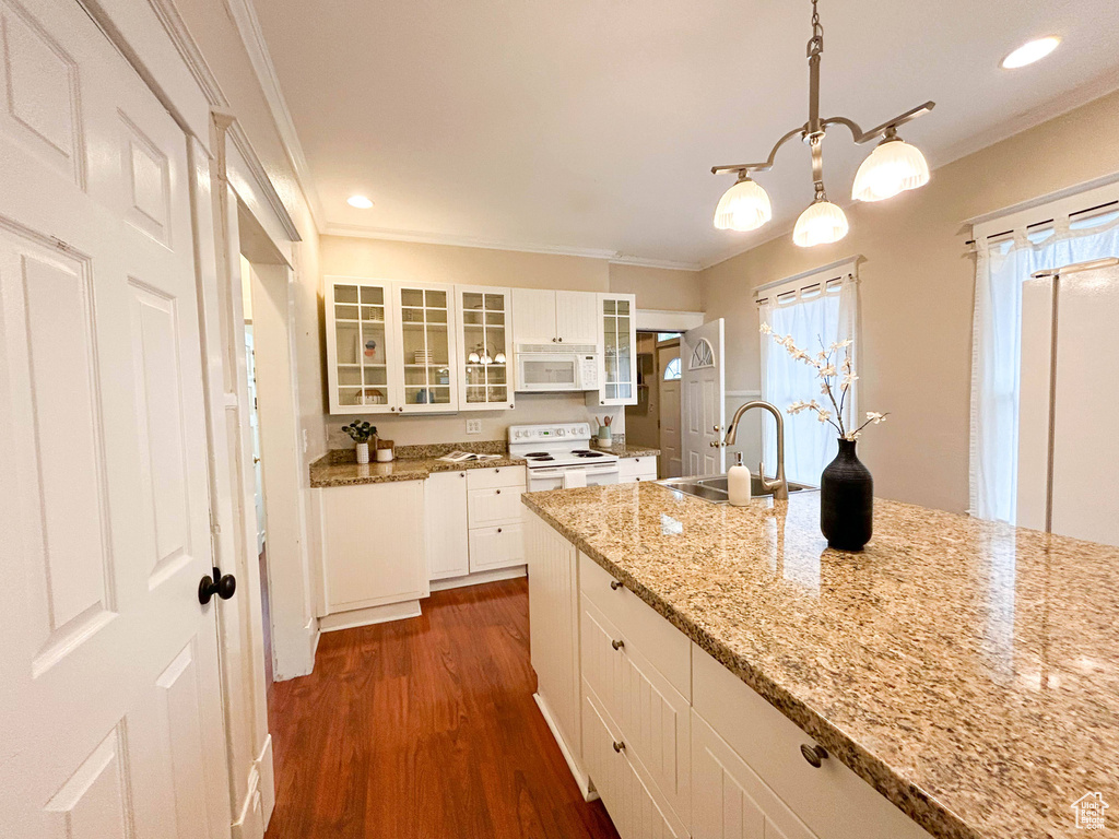 Kitchen featuring white appliances, sink, dark hardwood / wood-style flooring, hanging light fixtures, and white cabinetry