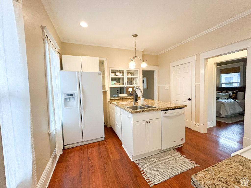 Kitchen featuring white cabinets, dark wood-type flooring, pendant lighting, sink, and white appliances