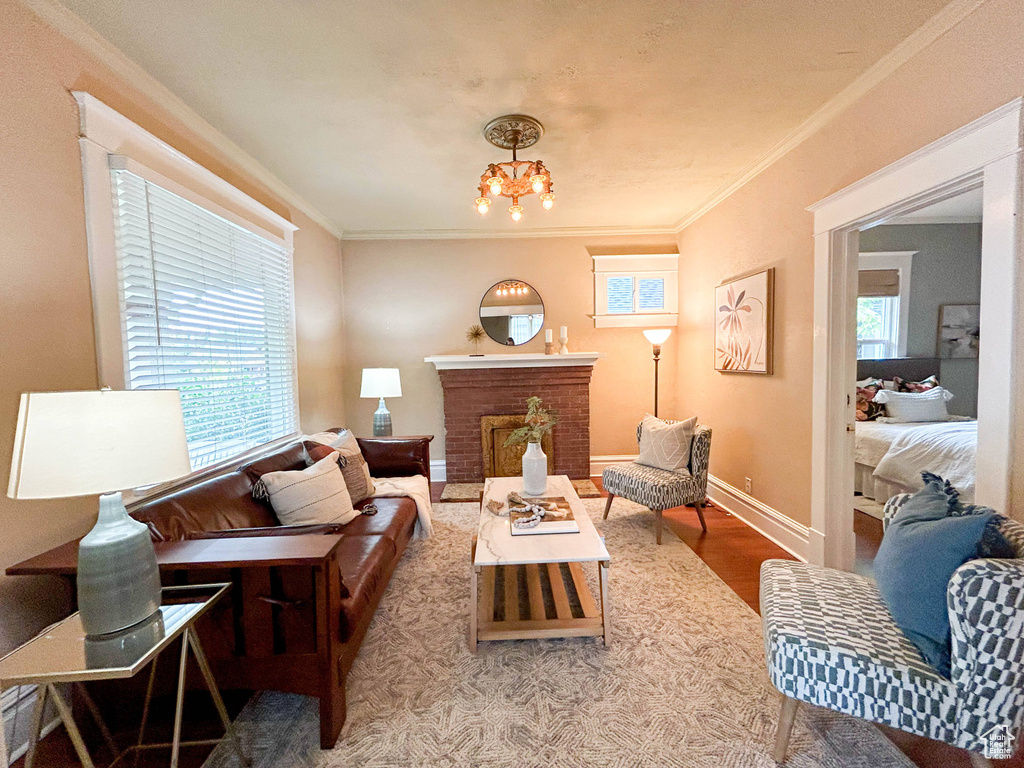 Living room with an inviting chandelier, ornamental molding, hardwood / wood-style floors, and a healthy amount of sunlight