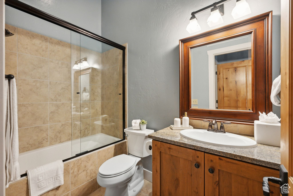 Full bathroom with toilet, enclosed tub / shower combo, and vanity