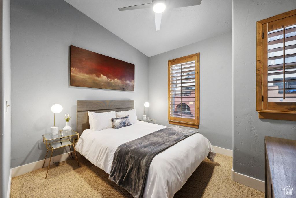 Carpeted bedroom featuring ceiling fan and lofted ceiling