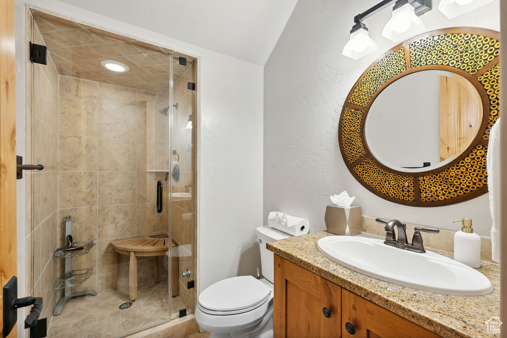 Bathroom with a shower with door, vanity, lofted ceiling, and toilet