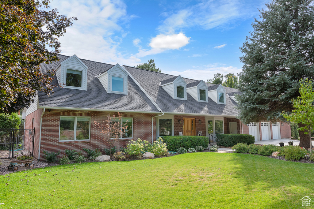 New england style home with a front yard, a garage, and covered porch