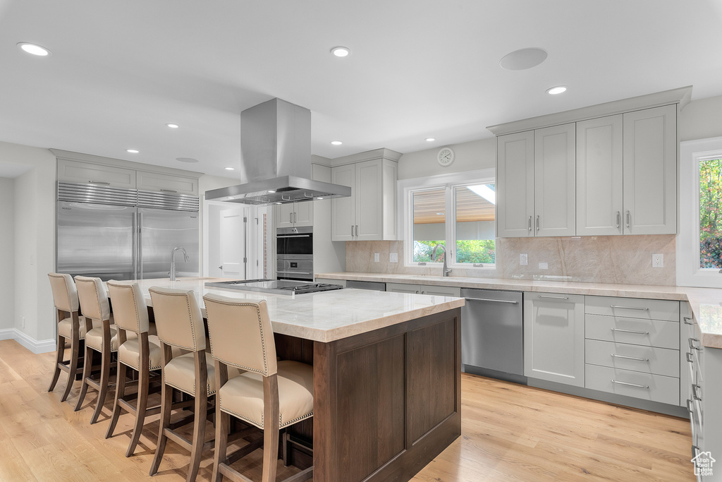 Kitchen featuring appliances with stainless steel finishes, island exhaust hood, a center island, and plenty of natural light