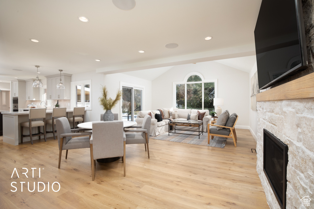 Dining area featuring vaulted ceiling, a fireplace, and light wood-type flooring