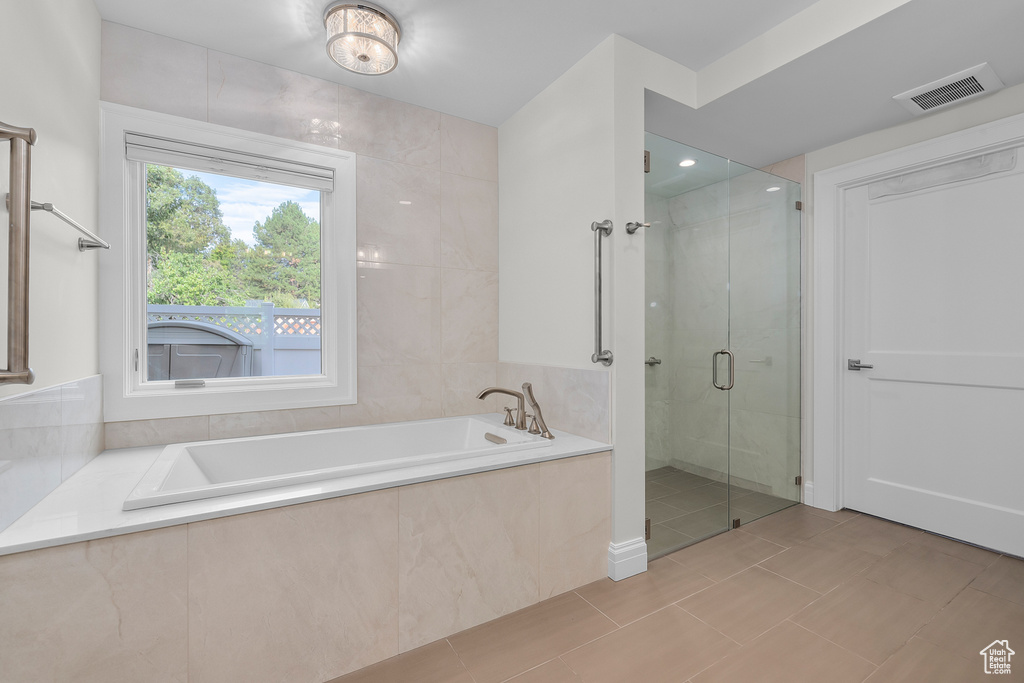 Bathroom featuring shower with separate bathtub and tile patterned flooring