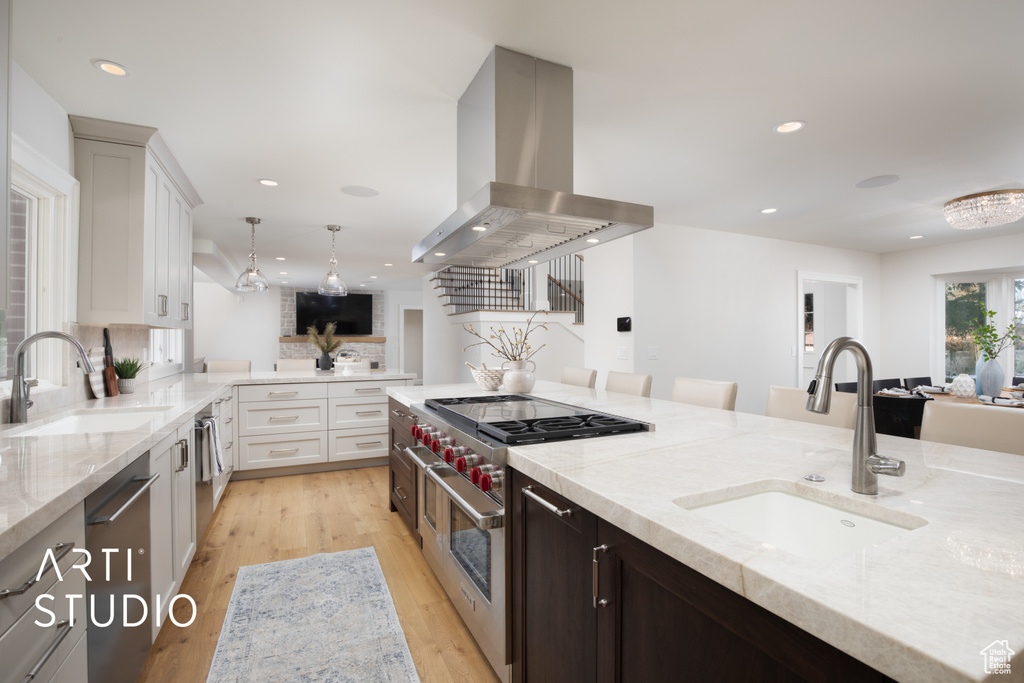 Kitchen featuring pendant lighting, appliances with stainless steel finishes, island range hood, and sink