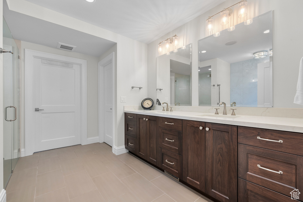 Bathroom featuring vanity, a shower with shower door, and tile patterned flooring