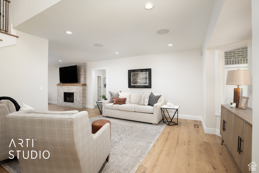 Living room with a stone fireplace and light wood-type flooring