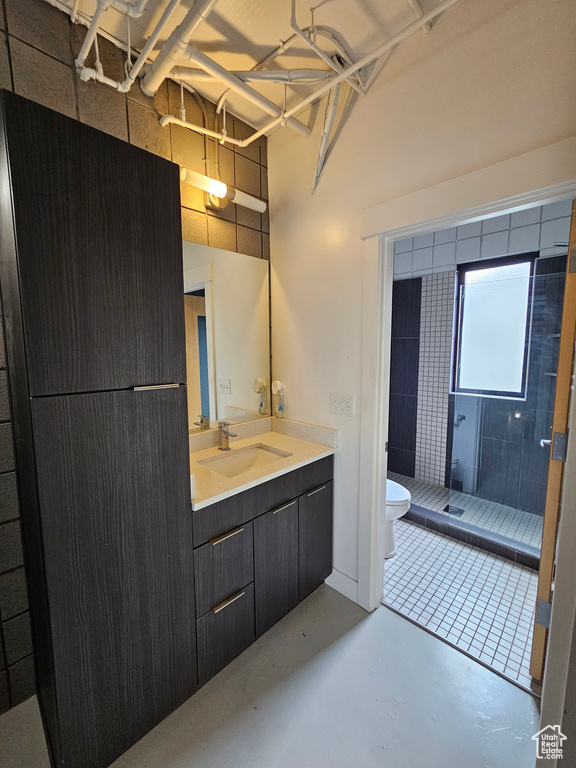 Bathroom featuring concrete floors, vanity, a shower, and toilet