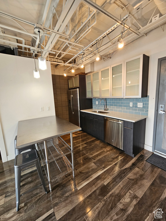 Kitchen with dark wood-type flooring, stainless steel appliances, decorative backsplash, and sink