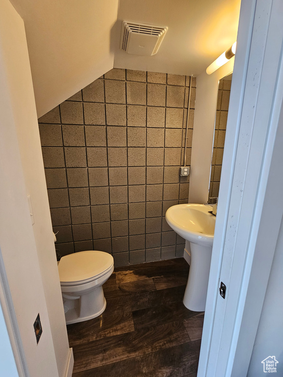 Bathroom with tile walls, hardwood / wood-style floors, and toilet