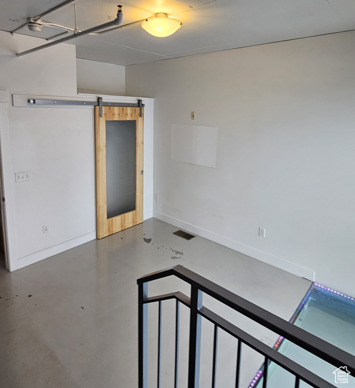 Empty room featuring a barn door and concrete flooring