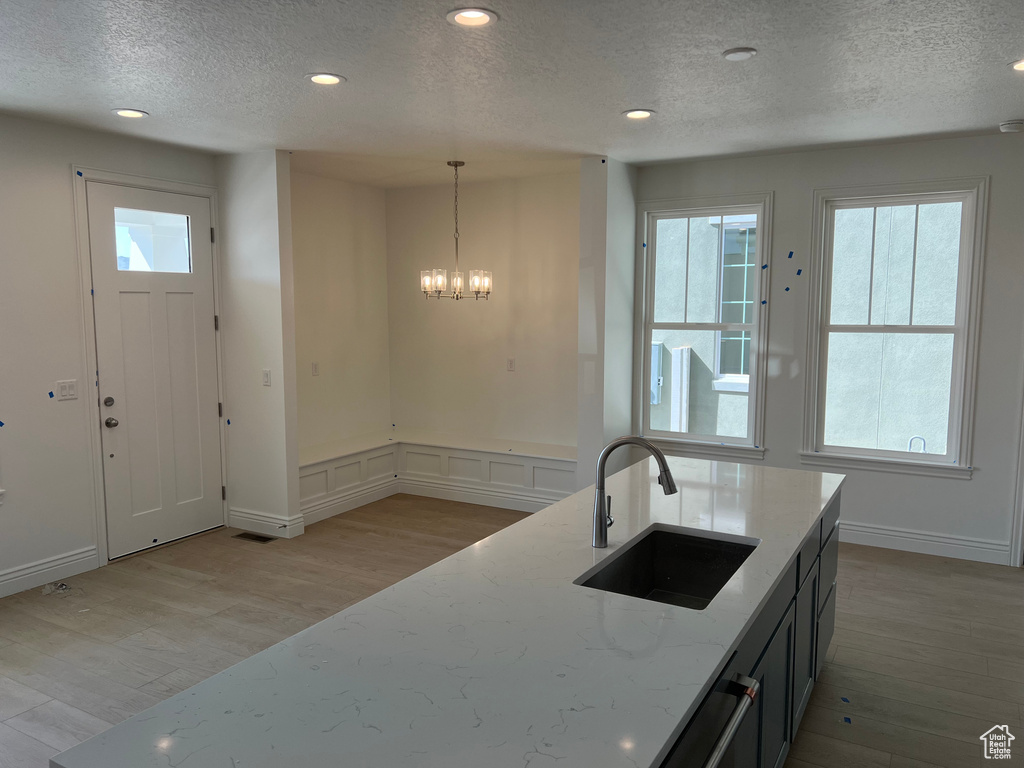 Kitchen with light wood-style floors, a sink, light stone countertops, and a wealth of natural light