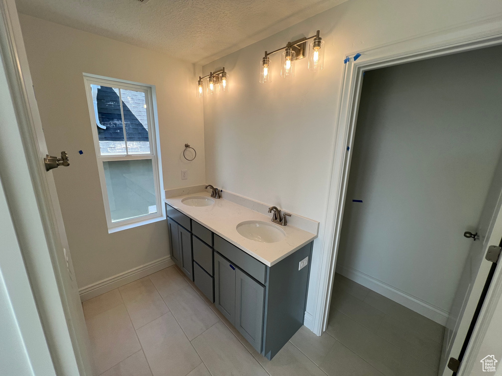 Full bath with baseboards, tile patterned floors, a textured ceiling, and a sink
