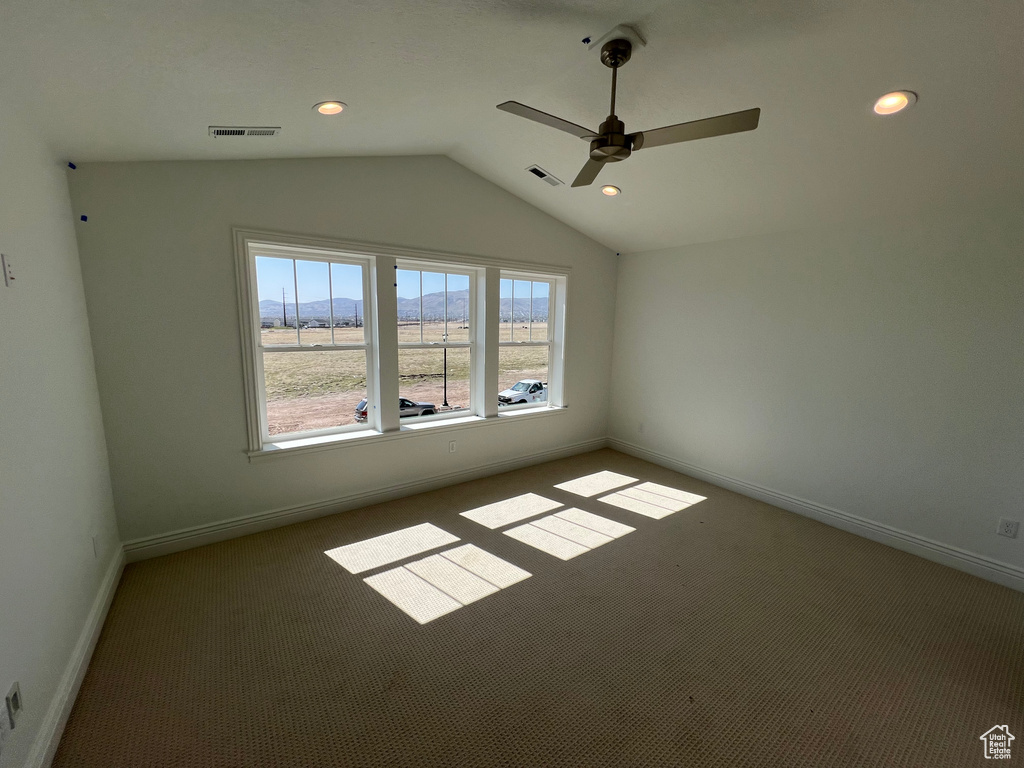 Carpeted empty room featuring visible vents, a ceiling fan, recessed lighting, and lofted ceiling