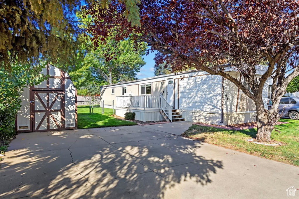 View of front facade featuring a front yard and a storage shed