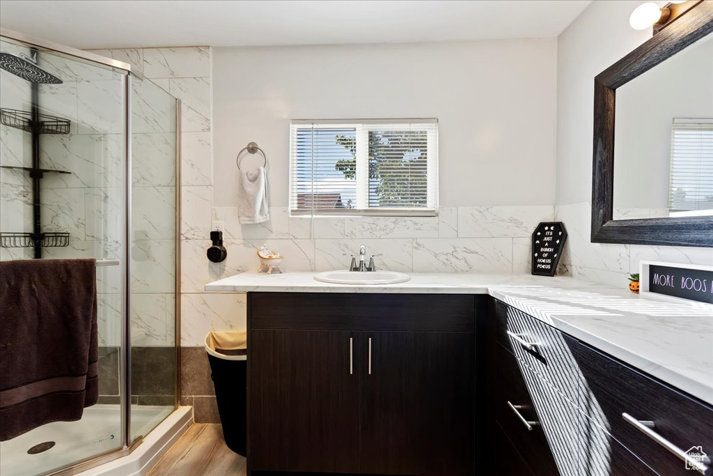 Bathroom with vanity, tasteful backsplash, an enclosed shower, and hardwood / wood-style floors