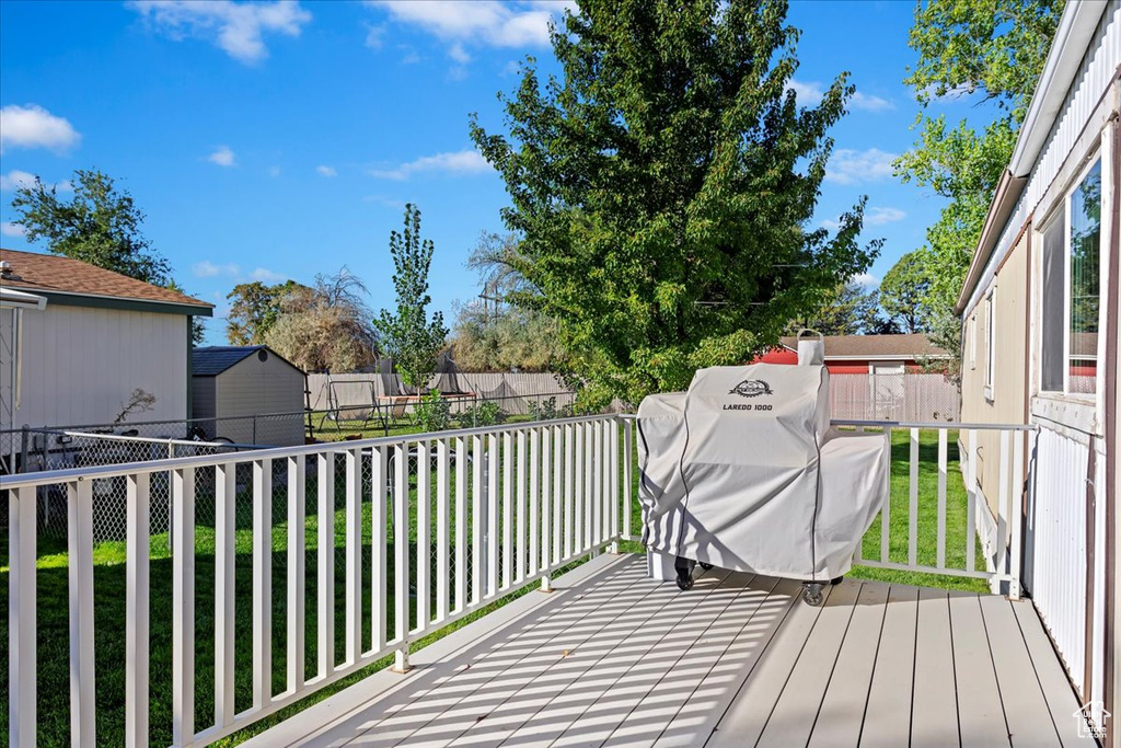 Wooden terrace featuring a storage unit and a yard