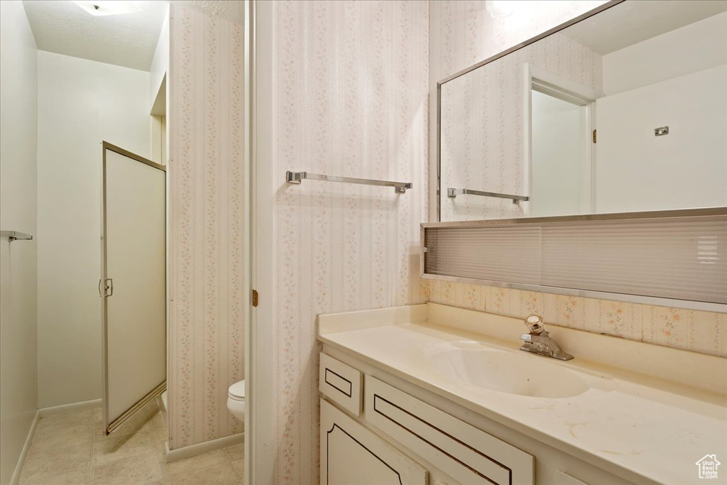 Bathroom with vanity, a shower, toilet, and tile patterned floors