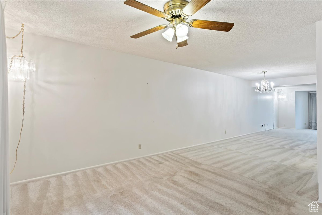 Carpeted spare room featuring a textured ceiling and ceiling fan