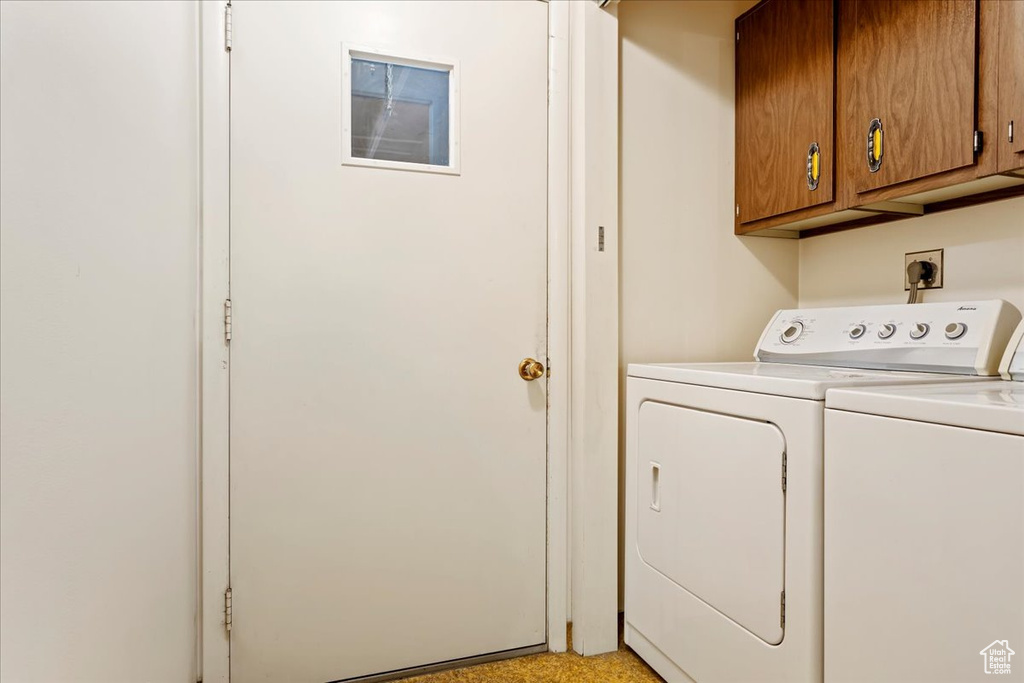 Laundry room featuring washing machine and clothes dryer and cabinets