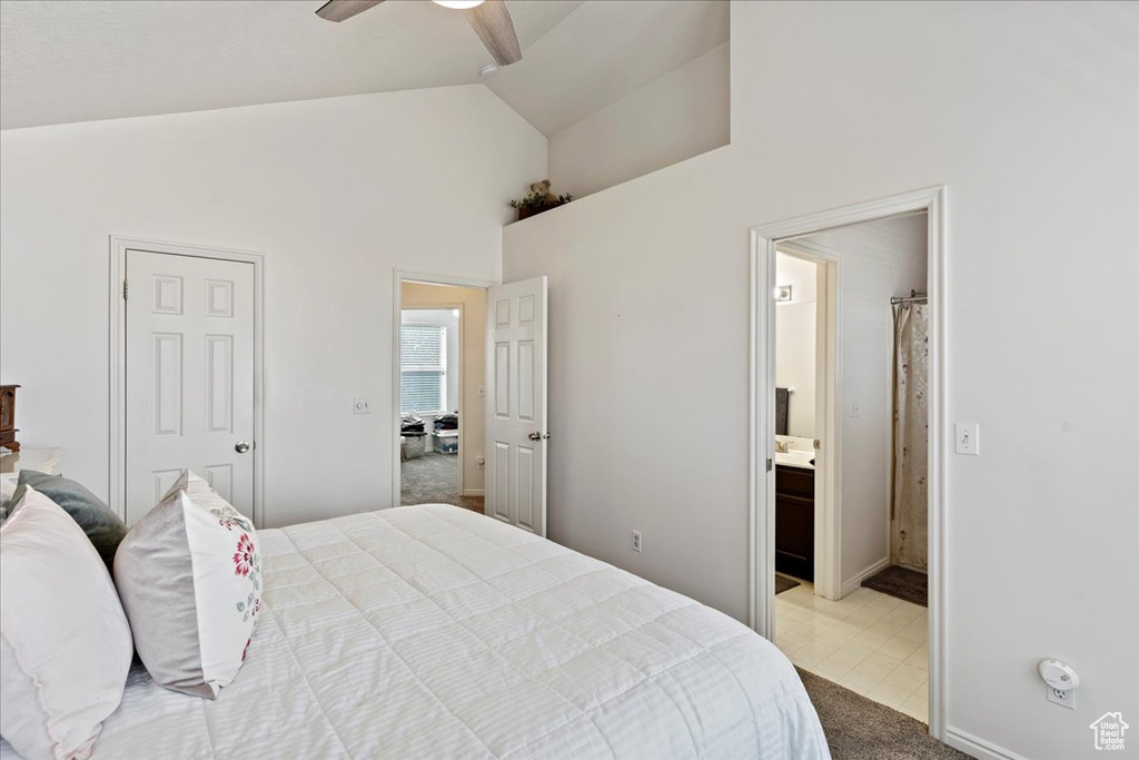 Carpeted bedroom with ensuite bathroom, high vaulted ceiling, and ceiling fan