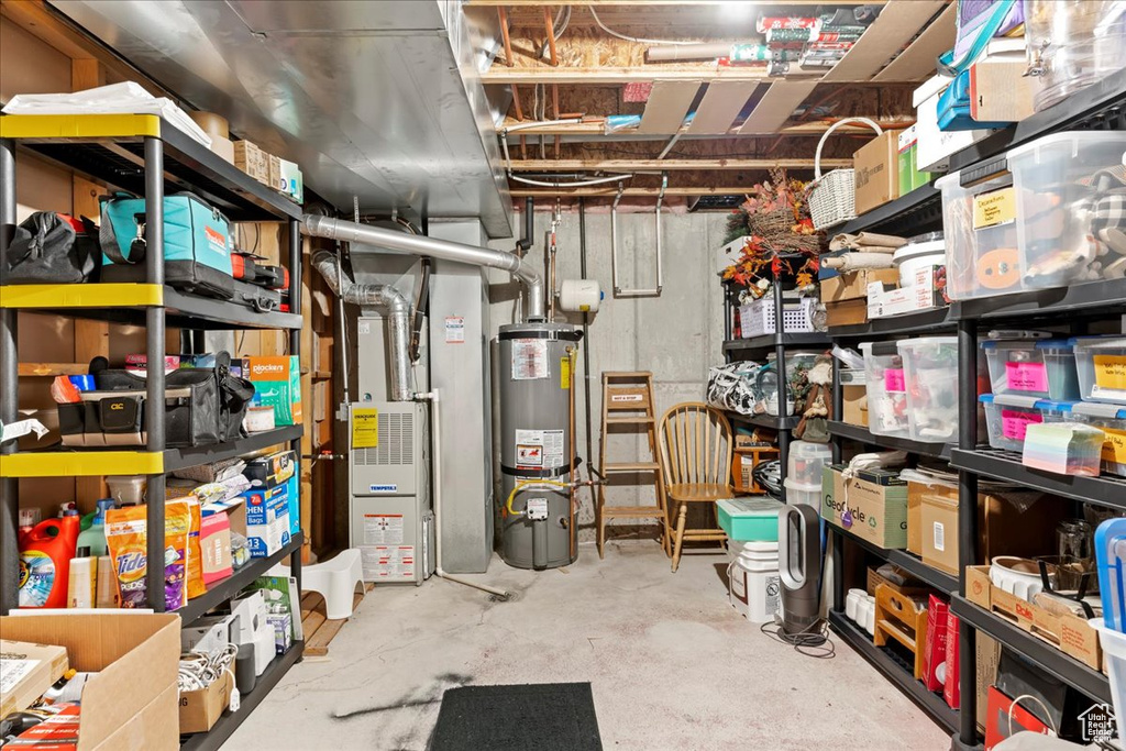 Storage room featuring water heater and heating unit