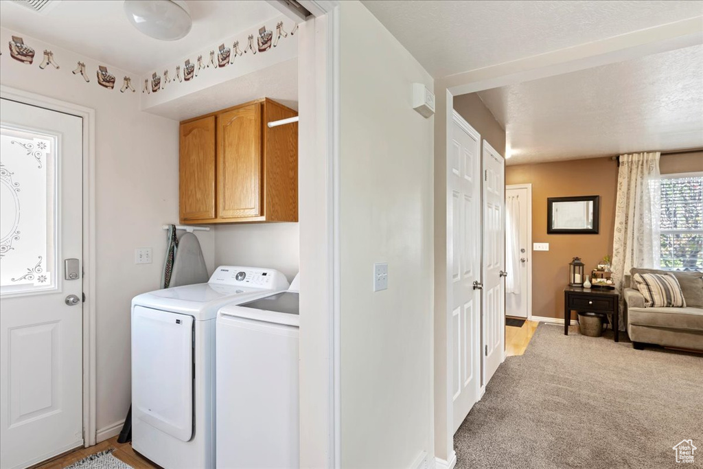 Laundry area featuring light carpet, cabinets, and washing machine and clothes dryer