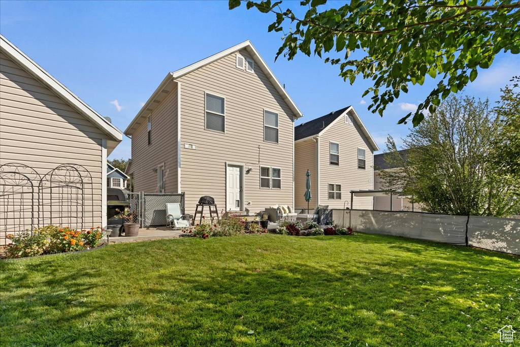 Rear view of house with a patio area and a lawn