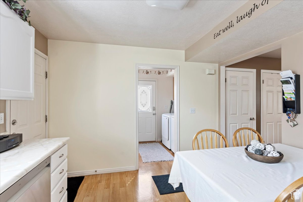 Dining area featuring light hardwood / wood-style flooring, a textured ceiling, and separate washer and dryer