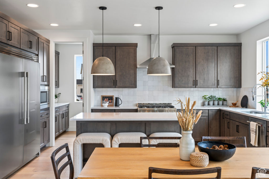 Kitchen featuring pendant lighting, dark brown cabinetry, light hardwood / wood-style flooring, sink, and stainless steel appliances