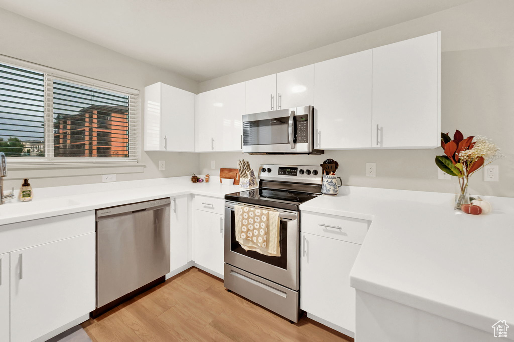 Kitchen featuring white cabinetry, stainless steel appliances, light hardwood / wood-style flooring, and sink