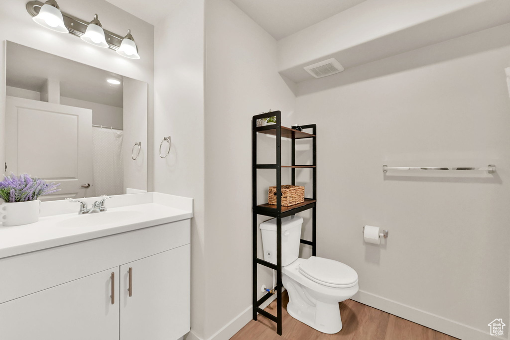 Bathroom with vanity, hardwood / wood-style floors, and toilet