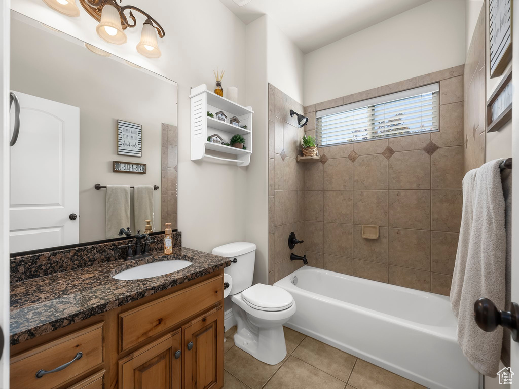 Full bathroom featuring vanity, tiled shower / bath combo, toilet, and tile patterned flooring