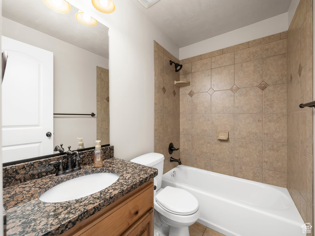 Full bathroom featuring vanity, tiled shower / bath combo, toilet, and tile patterned flooring