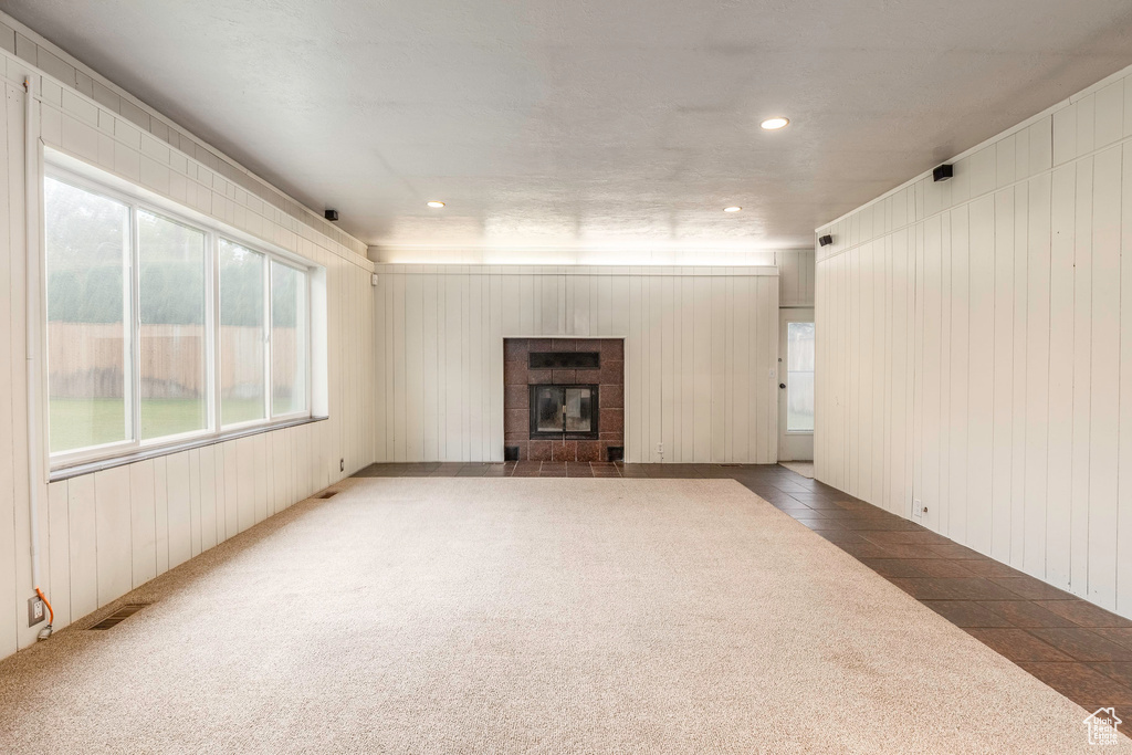 Unfurnished living room featuring wood walls, carpet, and a fireplace