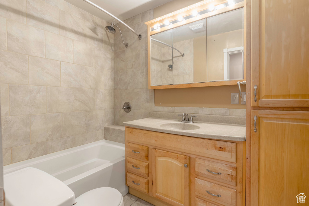 Full bathroom featuring tiled shower / bath, vanity, toilet, and tile patterned floors