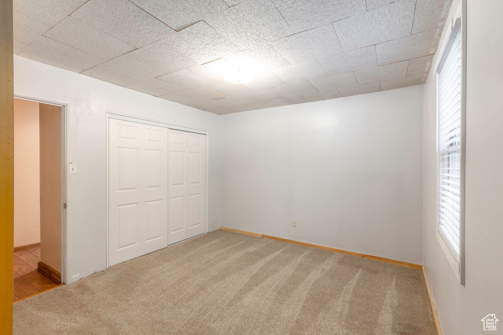 Unfurnished bedroom featuring a closet, multiple windows, and carpet floors