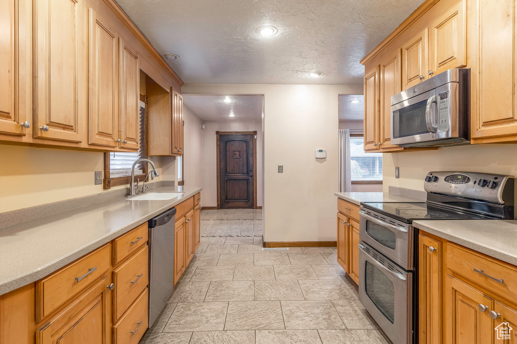 Kitchen with a textured ceiling, stainless steel appliances, and sink