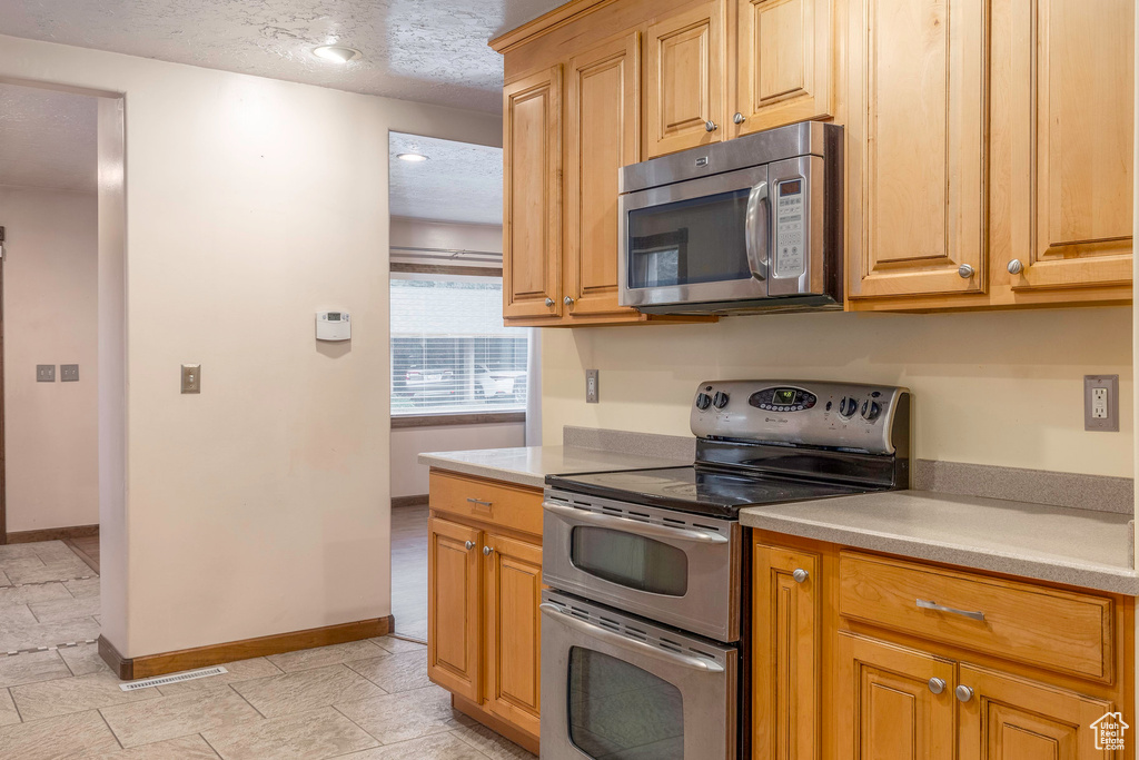 Kitchen with appliances with stainless steel finishes and a textured ceiling