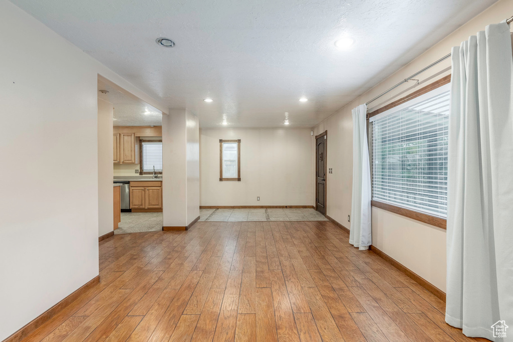 Unfurnished room featuring light hardwood / wood-style floors, a healthy amount of sunlight, and sink