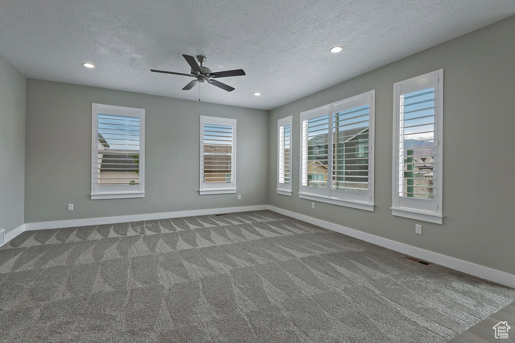 Carpeted spare room with ceiling fan and a textured ceiling